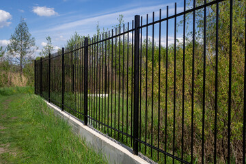 Metal fence on a cement foundation against the blue sky. Diagonal arrangement