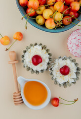 top view of ripe rainier cherries in a bowl with cottage cheese in mini tart tins and honey on...