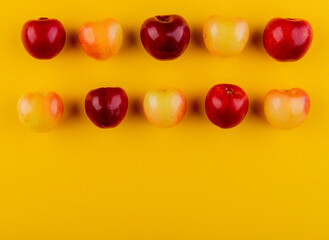 top view of ripe red and yellow cherries isolated on yellow background with copy space