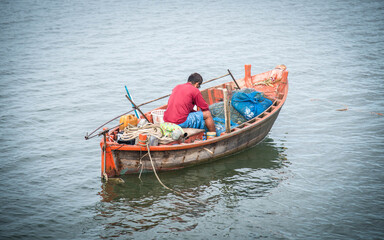 Local fishermen take fish from their nets on a boat in the middle of the sea, Bang Phra, Thailand,...
