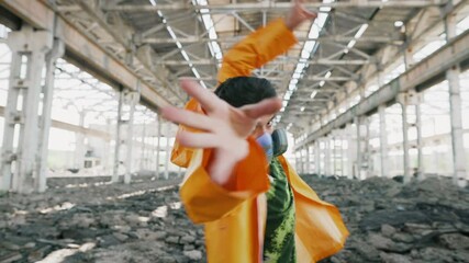 Young male dancer in protective mask performing various freestyle dance in ruined abandoned building