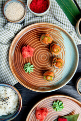 top view of set of baked sushi rolls with wasabi and ginger on a plate