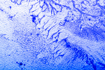 Paint spilled and smeared over a textured plastic surface. Light overlay pattern with dried paint texture. Blurred image at an angle