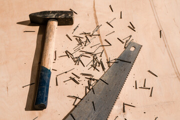 Hammer, nails and saw on wood background