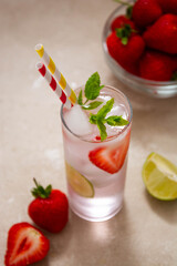 Summer cold refreshing fruit drinks cocktail with strawberry, lime and mint.