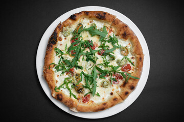top view of seafood pizza with shrimp, mussels and arugula on black background