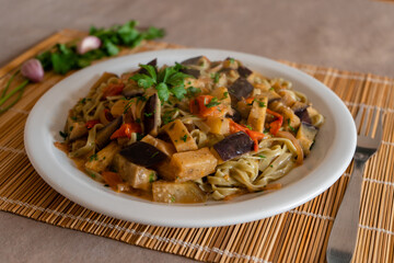 Close-up of spinach noodles with sautéed vegetables. Healthy food concept.