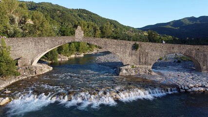 Fototapeta na wymiar Europe, Italy , Bobbio , Piacenza - Drone aerial view of roman historic stones bridge Ponte Gobbo o Ponte Vecchio pass over the river Val Trebbia