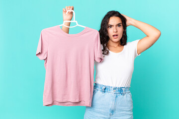 hispanic pretty woman feeling stressed, anxious or scared, with hands on head choosing a cloth