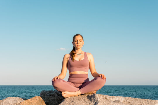 Woman practicing yoga in Lotus pose on beach