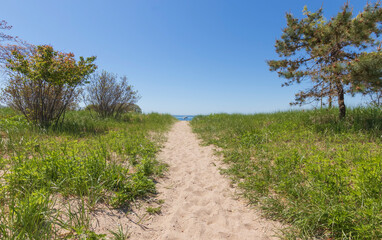 Fototapeta na wymiar sandy beach pathway to ocean with boat in background