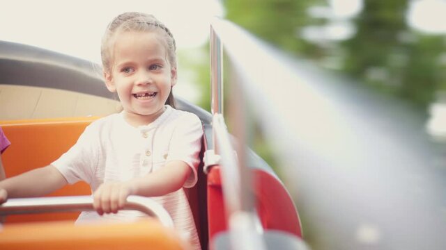 Child Ride Carousel Amusement Park Summer Day. Caucasian Little Girl Have Fun When Sitting Rotating Carousel Screaming Smiling Enjoy High quality 4k footage
