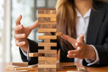 businesswoman holds her hand on a wooden block with a weak base. It is like a business risk...