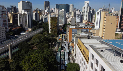 Aerial view of a public street market in downtown Sao Paulo, Brazil. A big vertical green wall on a residential building is seen on the left.