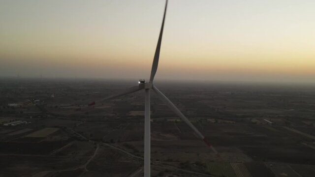Large wind turbines with blades in field aerial view bright orange sunset