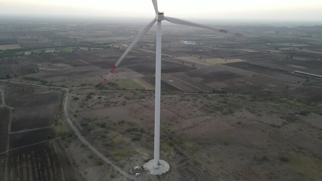 Large wind turbines with blades in field aerial view bright orange sunset