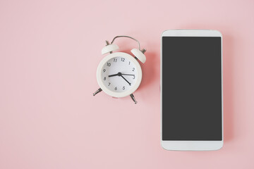 white mobile phone with clipping on touchscreen and analog alarm clock on sweet pastel pink background for dating, meeting, appointment or deadline concept