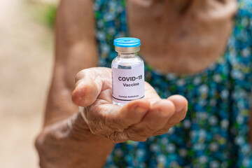 Elderly woman holding COVID-19 vaccine.