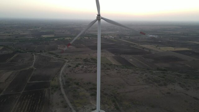 Large wind turbines with blades in field aerial view bright orange sunset