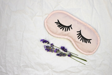 Sleep mask with natural lavender on white bedding.