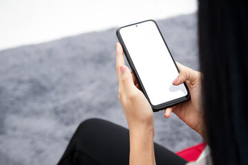 woman holding a black smartphone with a white screen Sit on the sofa in the living room. online technology concept Connect to communication via the Internet.