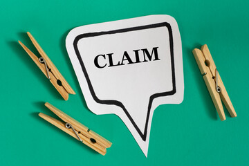 CLAIM - word on white sticky note with wooden clothespins on green background