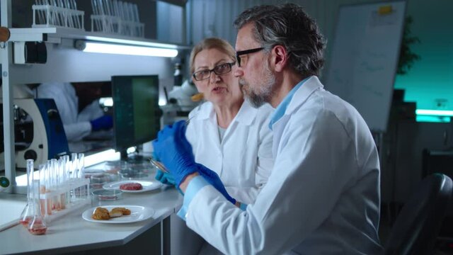 Mature scientists trying samples of cell based meat