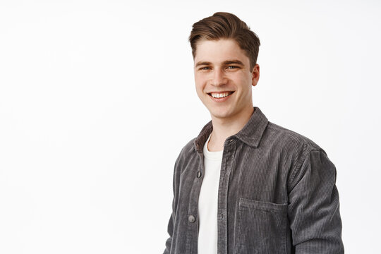 Close up of young candid guy, handsome man smiling white teeth, standing relaxed and casual against isolated studio background, looking happy, white background