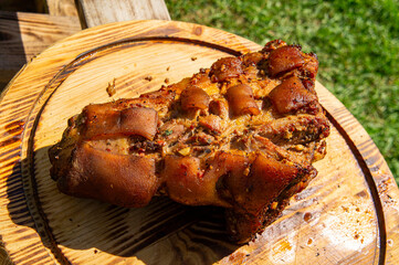 Grilled pork leg shank on wooden round cutting board close up