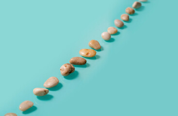 Small brown stones, similar to pebbles, lie diagonally on a turquoise background.