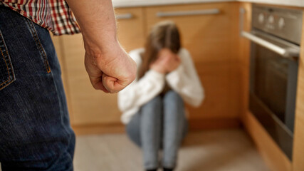 Mad man beating and threating young woman crying on floor. Concept of domestic violence, parent...