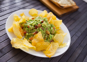 traditional soft avocado salad. Guacamole with chips on a plate