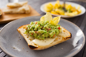 toasted slices of square bread with warm cheese and homemade guacamole on plate for healthy breakfast