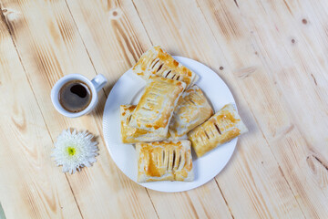 Small cup of black coffee, cookies on white plate,  daisy chrysanthemum flower on wooden table
