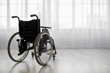 Wheelchair against window, in bright living room or hospital interior