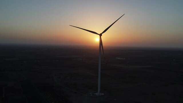 Large wind turbines with blades in field aerial view bright orange sunset