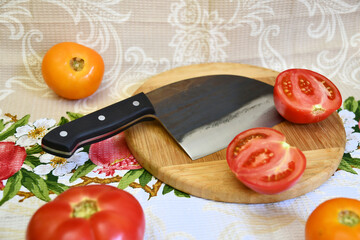 Knife cleaver cutting edge red yellow fresh tomato sliced fetus cooking food wooden plate gray background 