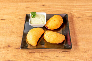 Colombian yellow corn empanadas stuffed with chicken stew with vegetables and green sauce for dipping