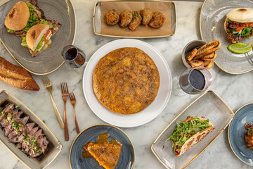 Fusion food plate set. Spanish omelette, fish tiradito, taco with arugula, sandwiches and marble table