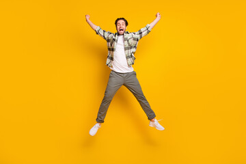 Fototapeta na wymiar Full length photo of cheerful young active man jump up good mood smile isolated on yellow color background