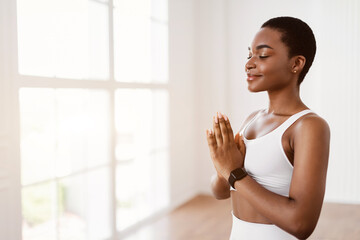 Black woman meditating keeping hands together in prayer pose - obrazy, fototapety, plakaty