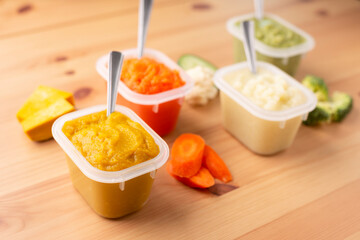 Close up of bowls with healthy baby food on wooden background..Pureed baby food make by carrot, broccoli and pumpkin