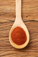 Closeup of red paprika pepper on a spoon over wooden table