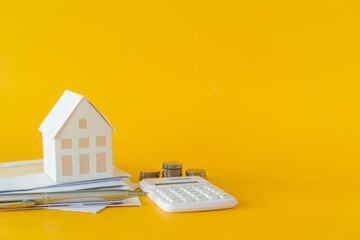 close up of home model and calculator and invoice letter on yellow background with space for money...