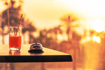 Ringing hotel service bell with welcome drink and sea, palm tree view on sunset. Travel concept....