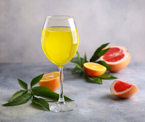 Summer. Drinks. Fruit tropical cocktail with orange, grapefruit in a transparent glass and a branch of greenery on a light gray background. Background image, copy space