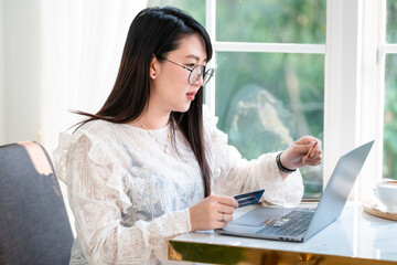 freelance people business female casual show holding a credit card working with laptop computer in coffee shop like the background,for online shopping and payment via internet.