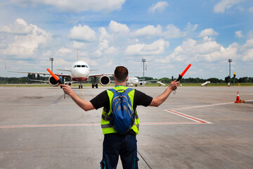 The traffic controller at the airport shows the semaphore with sticks to the pilot of the plane...