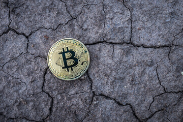 Golden Bitcoin Coin on dry cracked ground background. Financial Crisis concept Bitcoin cryptocurrency.