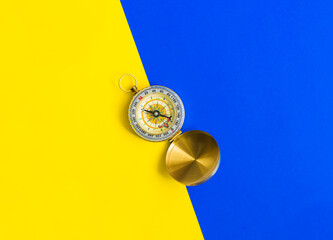 Golden color compass on yellow and blue background, direction